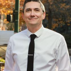 Luca smiles while wearing a white shirt and black tie