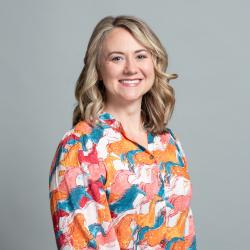 Caylie smiles, wearing a colorful shirt