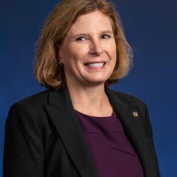 Judy smiles in front of a blue background 