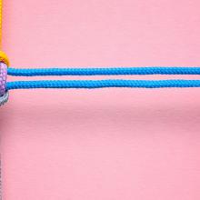 Four colored ropes knotted together on a pink background