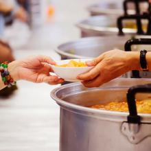 Someone handing off a plate of food to another person