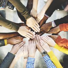 Many peoples' hands in the center of a circle.