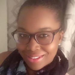 Patriece smiles to camera wearing glasses and scarf.